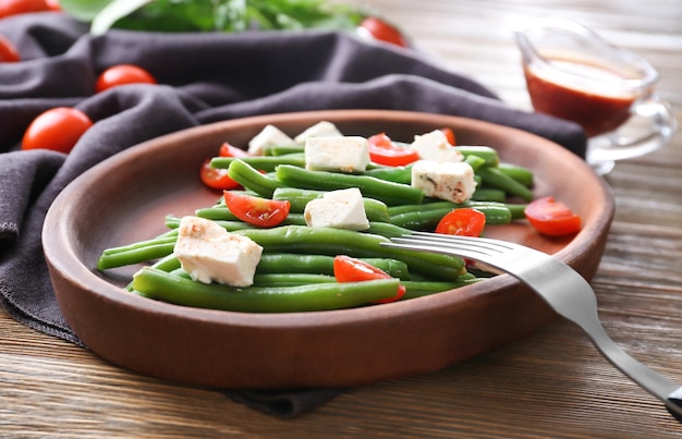 Plate with delicious green beans salad on wooden table