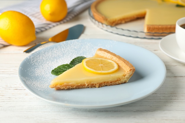 Plate with delicious lemon tart on white wooden background, close up