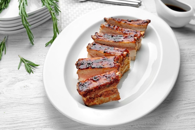 Plate with delicious pork ribs on wooden table