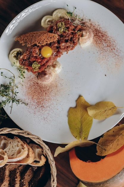 Plate with delicious tartare, toasted bread and salad on a wooden table.