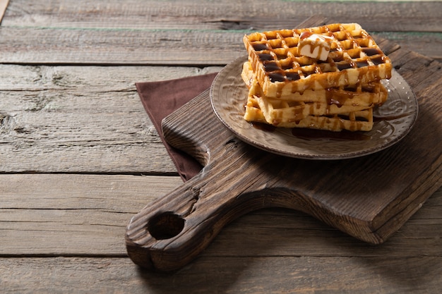 Plate with delicious waffles poured with caramel topping