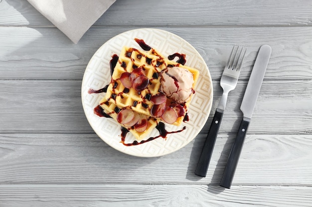 Photo plate with delicious waffles on wooden background