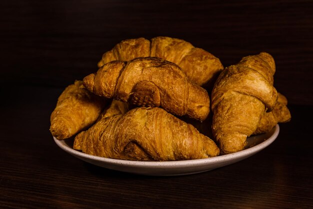 Plate with fresh croissants on a dark wooden table