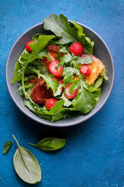 Plate with fresh salad of arugula, plants, cheese, basil and strawberry. Top view food.