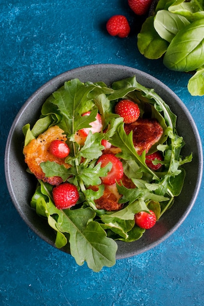 Plate with fresh salad of arugula, plants, cheese, basil and strawberry. Top view food.