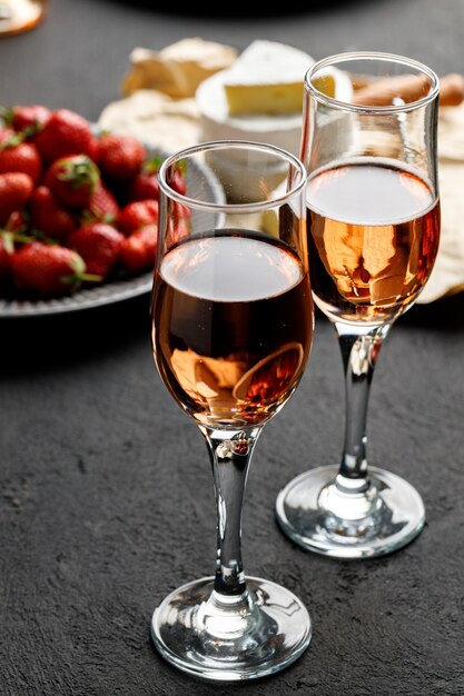 Plate with fresh strawberry and glass of wine on black background close up