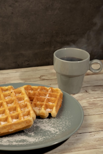 Plate with freshly baked waffles with a cup of hot black coffee concept breakfast snack pastries