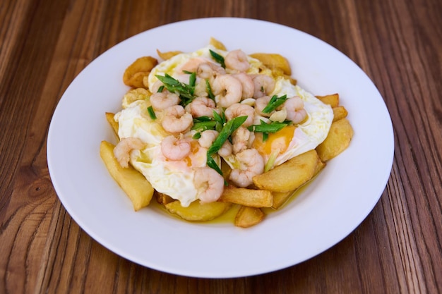 plate with fried eggs french fries garlic sprouts and grilled prawns