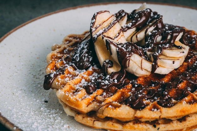 Plate with gourmet waffles with chocolate and banana slices