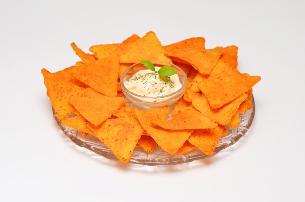 Plate with mexican chips and sour cream sauce on a white background serving method