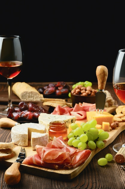 Plate with prosciutto, grapes, honey, dates, crackers, nuts and wine