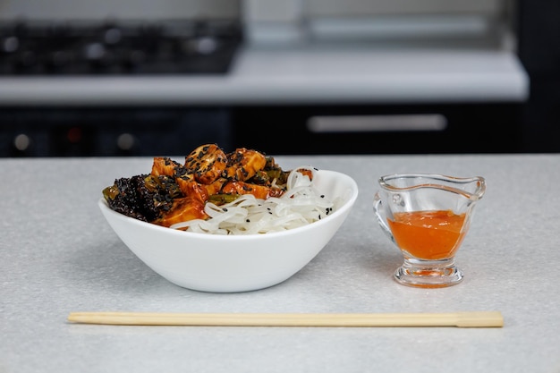 Plate with rice noodles and chicken Food sticks Dark home kitchen background