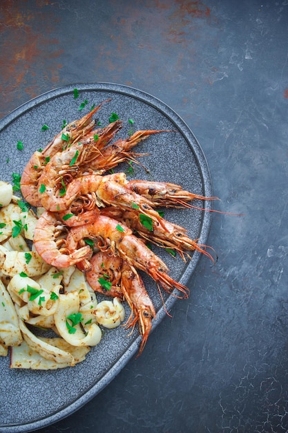 Plate with seafood, King prawns and squid, Fish menu in the restaurant, Dark background