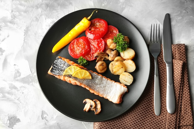 Plate with slice of delicious salmon on table