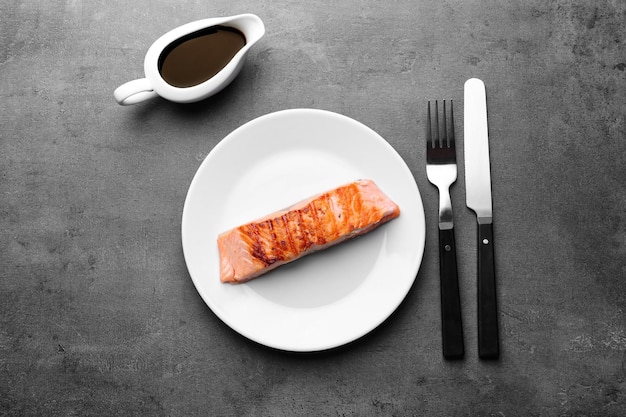 Plate with slice of delicious salmon on table