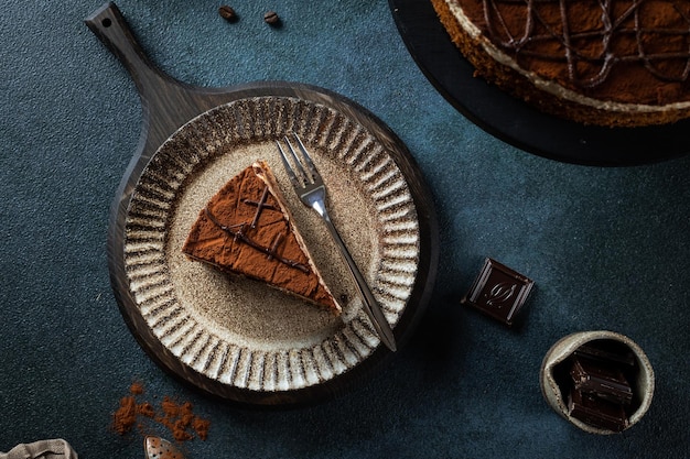 Plate with slice of tasty homemade chocolate cake on blue background Space for text Cake flatlay Piece of chocolate cake