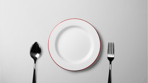 Plate with spoon and fork on white table _isolated background stock photograph