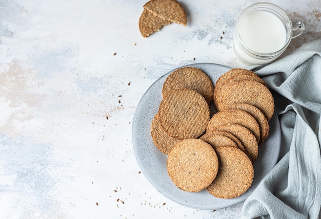 Plate with tasty crackers and a cup of milk. Snack or breakfast on grey stone background. Top view.