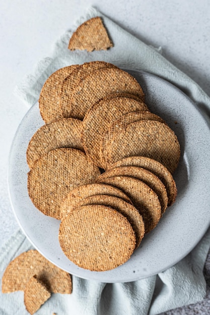 Plate with tasty crackers with sesame and flax seeds on grey stone background