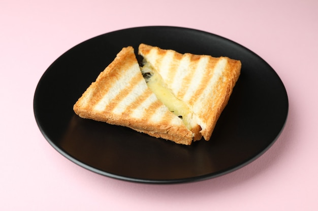 Plate with tasty grilled sandwich on pink background