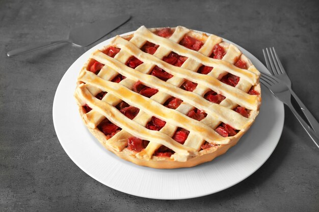 Photo plate with tasty strawberry rhubarb pie on table