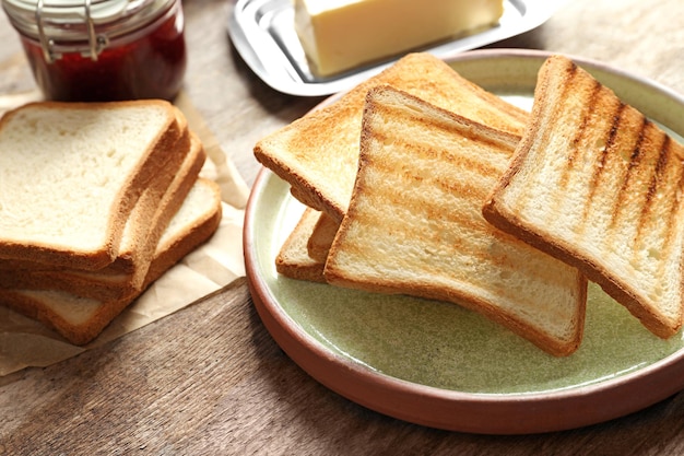 Plate with tasty toasted bread on wooden table