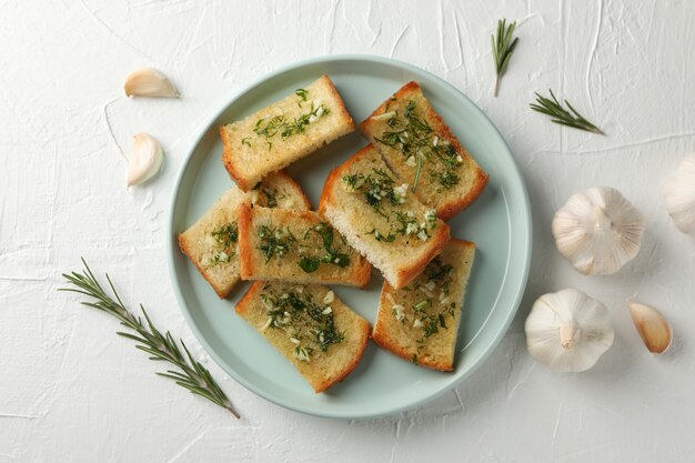 Plate with toasted garlic bread on white, top view