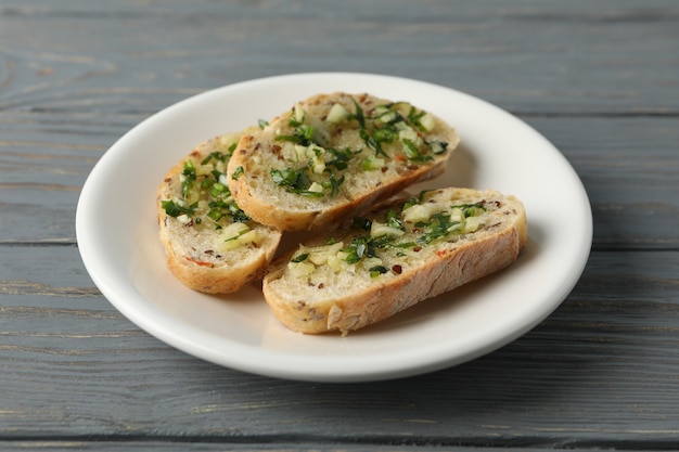 Plate with toasted garlic bread on wooden, close up