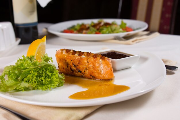 Photo plated grilled fish with garnishes and sauce on restaurant table