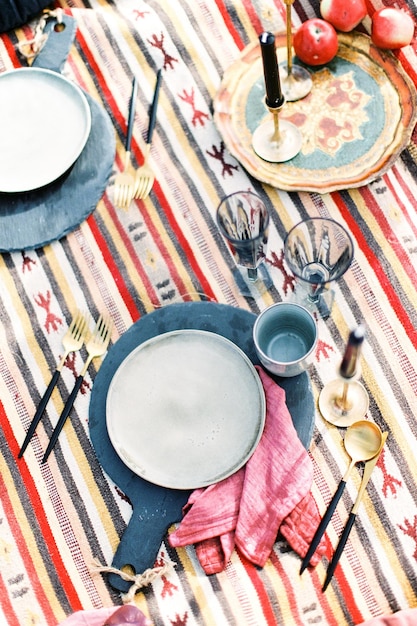 Plates glasses and candles on a colorful homespun bedspread top view