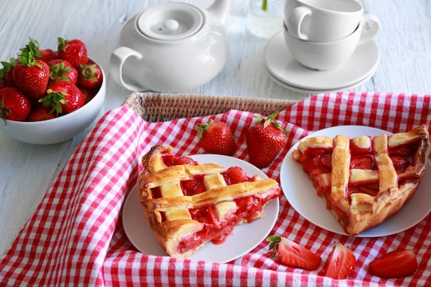 Plates with delicious strawberry cake in tray on table