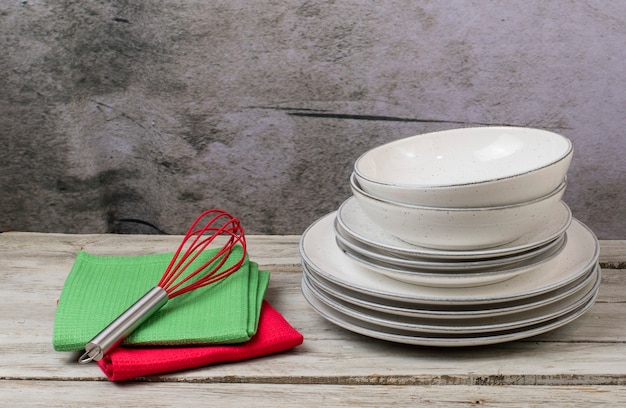 Plates with kitchen towels and cooking utensils on a wooden table