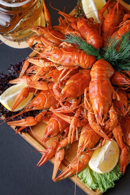 A platter of cooked crayfish with lemons on the side.