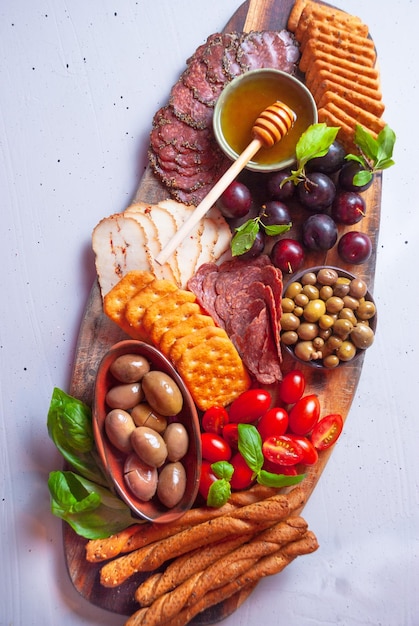 A platter of meats, cheese, and olives with honey.