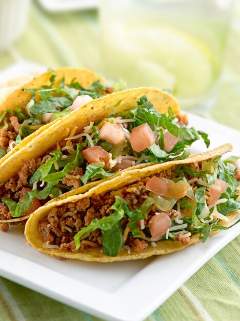 A platter of three tacos on white plate