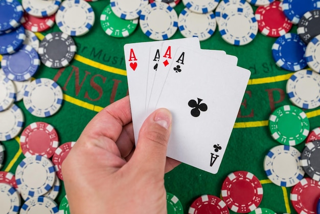 The player holds playing cards in his hand on a green table in a casino with chips gamble