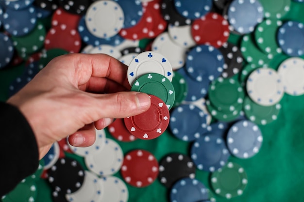 the player holds poker chips. Male casino player holding chips with a poker chips on the background.