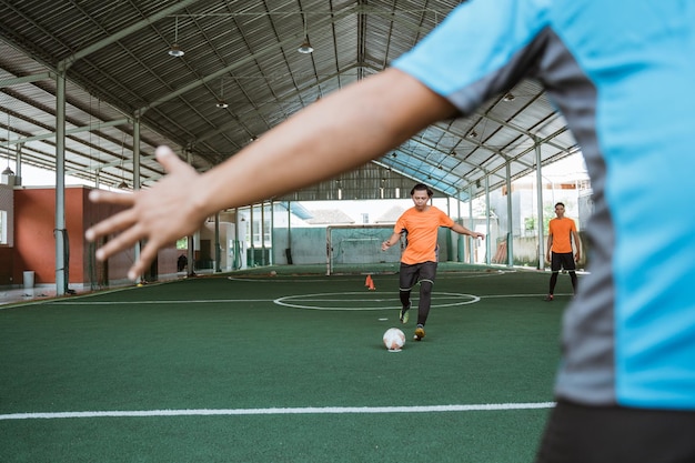 Player kicks the ball towards the goalkeeper while playing futsal