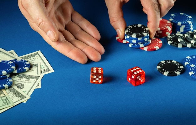 The player places a bet in a dice game or craps on a blue table in a casino