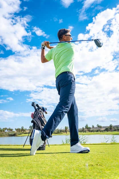 A player playing golf on the golf course hitting the ball next to a lake vertical photo