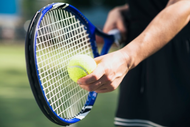 Player's hand with tennis ball and racket