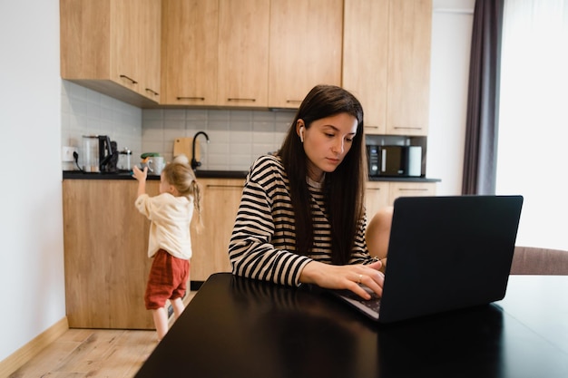 Playful child distracts from work kid making noise and asking attention from busy mom