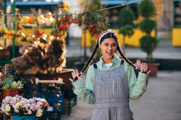 Playful farmer woman in denim overalls smiling sincerely while posing