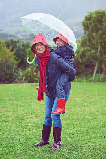 Playful in the rain Cropped portrait of a mother carrying her son on her back outside in the rain