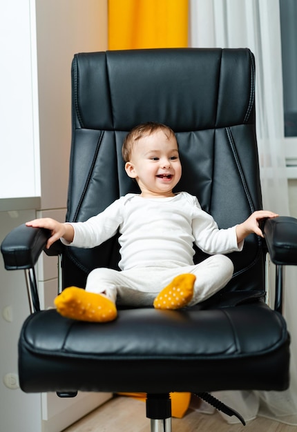 Playful small boy sitting on chair Little kid playing on a chair