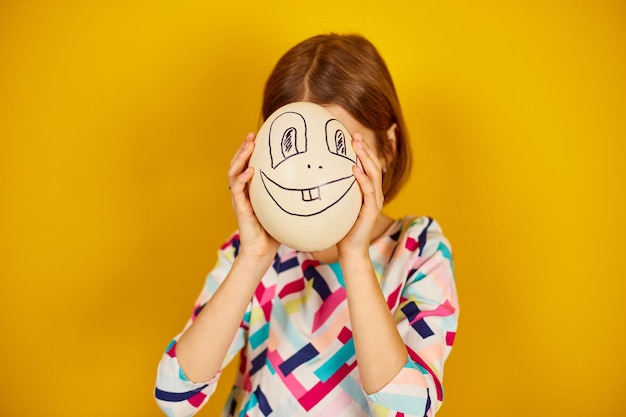 Photo playful teenager girl covering her face of ostrich egg with funny face