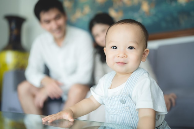 Playful young mother playing with toddler baby sitting on father lap on couch at home