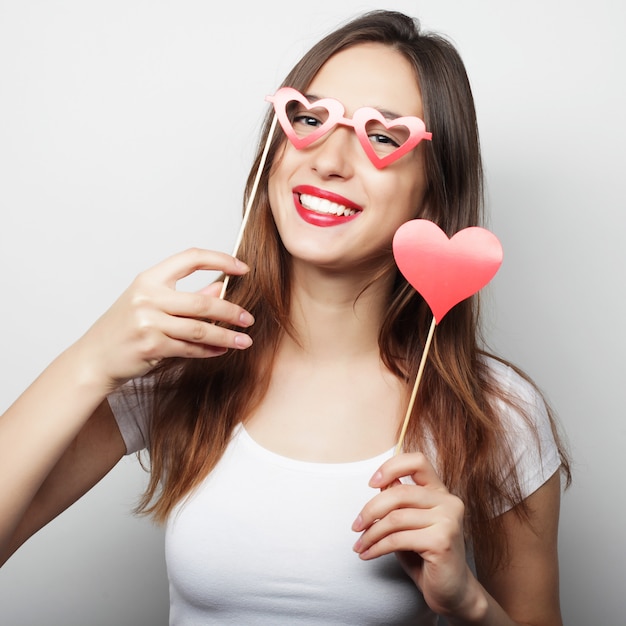 Playful young woman holding a party heart.