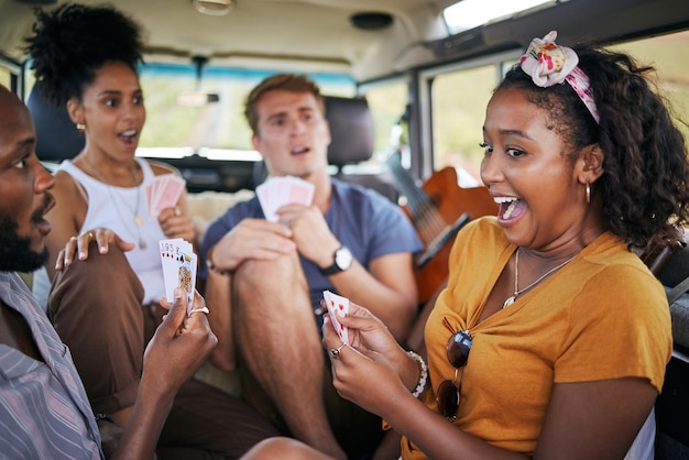 Playing cards road trip and friends in van winning and excited for adventure journey holiday and youth games lifestyle Diversity group of people camping and winner with card game in a caravan car