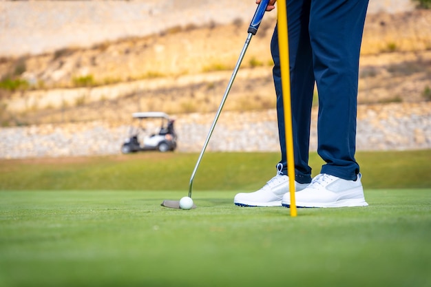 Playing golf at golf club on the green hitting the ball with the putter near the hole and the flag